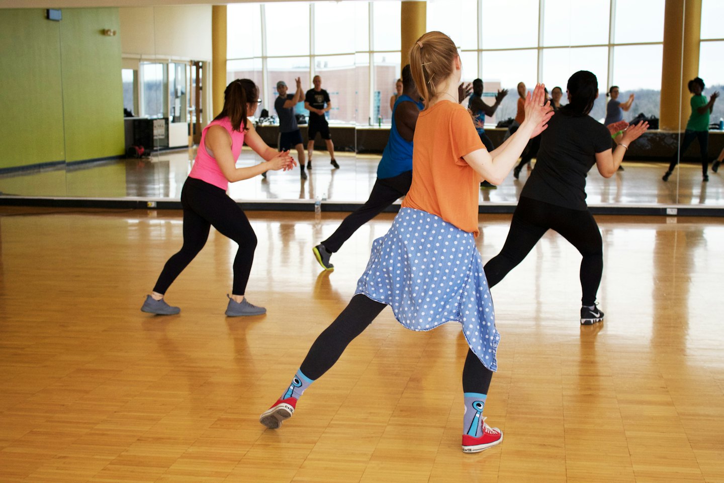 Diverse people enthusiastically exercising in a bright, modern fitness studio.